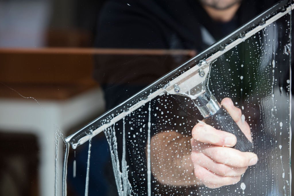 A soapy window with a squeegee cleaning the glass